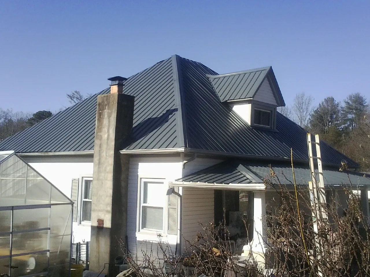 Dark blue standing seam metal roof on a white farmhouse with dormer — Slate & Tile Roof Repair by Roofing Brothers in Saint Charles